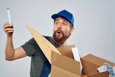 man in work uniform with box in hands tools lifestyle light background