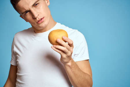 Happy man with fresh fruits gesturing with hands blue background white t-shirt vitamins orangesの写真素材