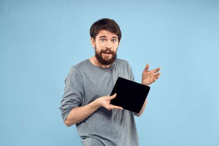 Man holding tablet in hands wireless technology internet lifestyle studio blue background emotions