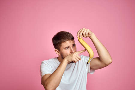 bearded man with banana in hand on pink background fun emotions model