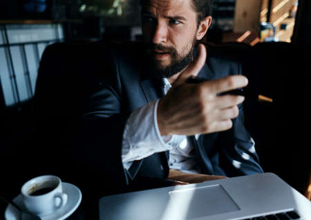 business man in suit in cafe in front of laptop with a cup of drink officialの写真素材