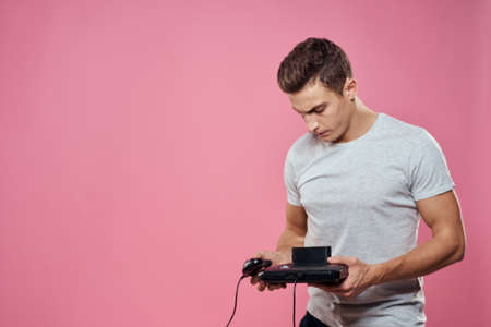 Cute man console in hands of video game entertainment lifestyle gray t-shirt pink background