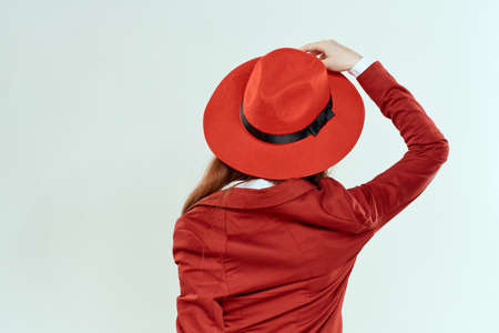 Woman in red hat and jacket back view elegant style light backgroundの写真素材