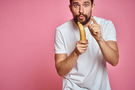 bearded man with banana in hand on pink background fun emotions model
