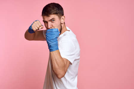 Sporty man in a white T-shirt boxing bandages on the hands of a workout lifestyle pink backgroundの写真素材