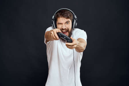 man in headphones with gamepad fun entertainment games lifestyle dark backgroundの写真素材