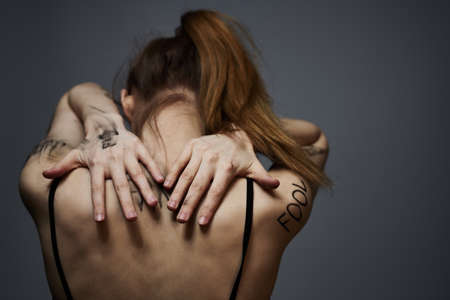 woman with offensive inscriptions on her body touching herself with hands stress frustration hateの写真素材