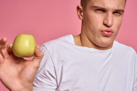 Man with fruits in hands on a pink background healthy food vitamins pink background white t-shirt modelの写真素材