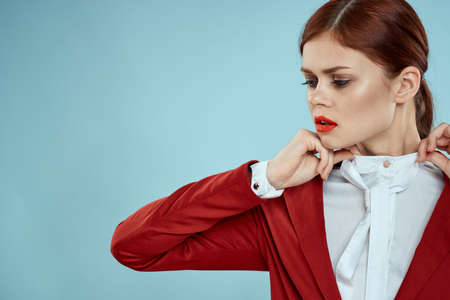 Elegant woman in red jacket bright makeup lips self-confidence cropped view blue backgroundの写真素材