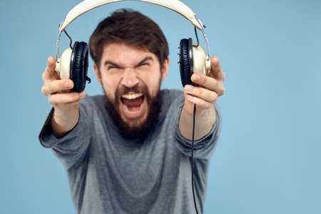 Man with headphones in hands music emotion technology lifestyle fun blue background close-upの写真素材
