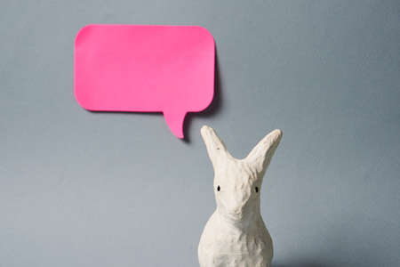 White Easter bunny with pink sticky note on gray background decoration animal Copy Space