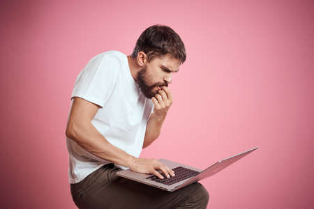 A man with an open laptop white t-shirt gestures with his hands cropped view new technology keyboard...