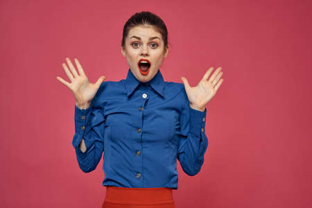 fashionable woman in blue shirt on pink background Red skirt emotions model gesturing with hands...