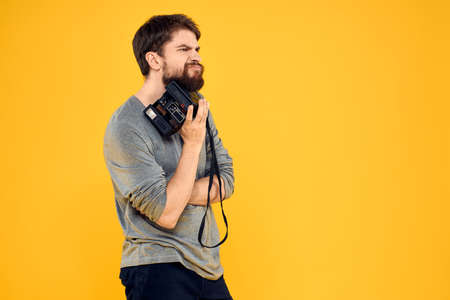 Male photographer with professional photo camera. Professional Creative approach studio yellow backgroundの写真素材