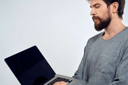 A man in a gray sweater with a laptop hands lifestyle technology communication internet workの写真素材