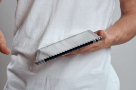 Tablet with a touch screen on a light background male hands white t-shirt cropped viewの写真素材