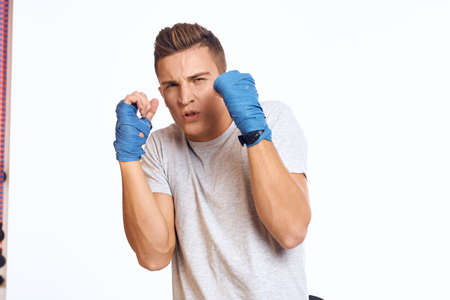 sporty male boxer in blue gloves practicing punches on a light background cropped viewの写真素材
