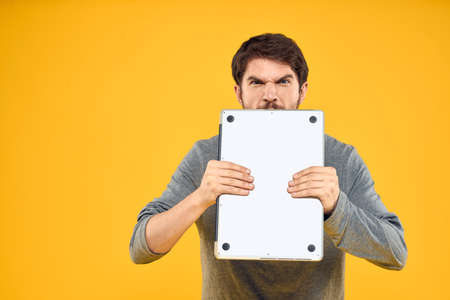 man with laptop wireless technology internet lifestyle work yellow isolated backgroundの写真素材