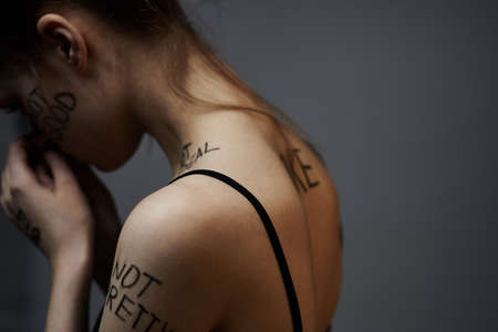 Woman with inscriptions on the body frustration and dissatisfaction emotions lifestyle gray backgroundの写真素材