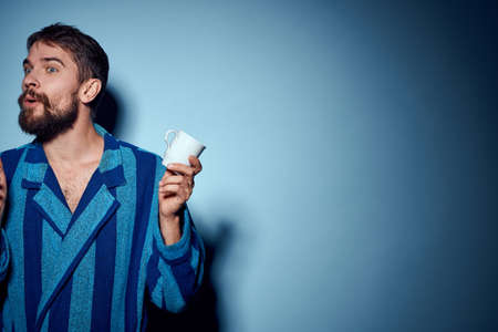 man in striped blue robe holding white cup in hand and emotions fun surprise model cropped viewの写真素材