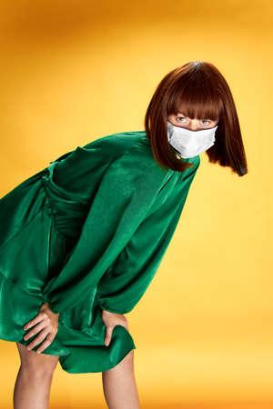 Woman in fashion dress posing in medical mask virus covid-19の写真素材
