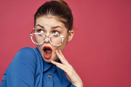 Portrait of a woman in glasses and in a blue shirt red lips pink background model