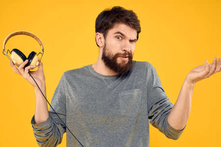 Man in headphones listens to music technology lifestyle fun people yellow background