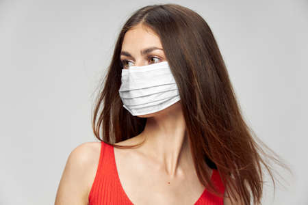 A woman in a medical mask looks to the side Red t-shirt close-upの写真素材