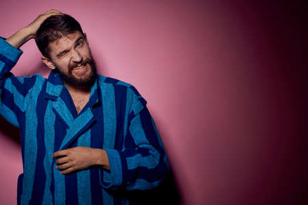 Bearded man in a blue striped robe on a pink background with hands emotions model portrait