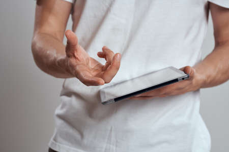 Tablet with a touch screen on a light background male hands white t-shirt cropped viewの写真素材