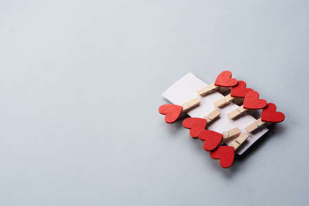 clothespins with hearts on a gray background and a sheet of cardboard
