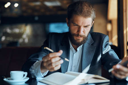 business man sitting at a table in a cafe documents work official coffee cupの写真素材