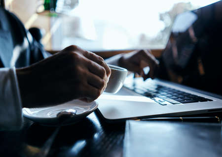 business man in a cafe at the table in front of a laptop work a cup of coffee at the table...
