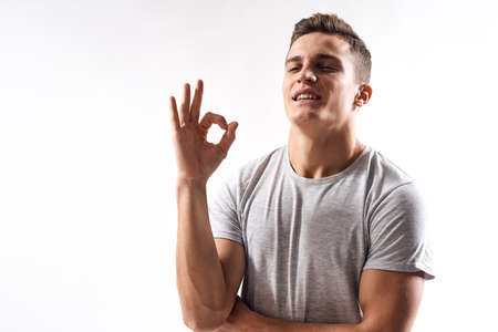 sporty man in white t-shirt on a light background gesturing with his hands cropped view Copy Space
