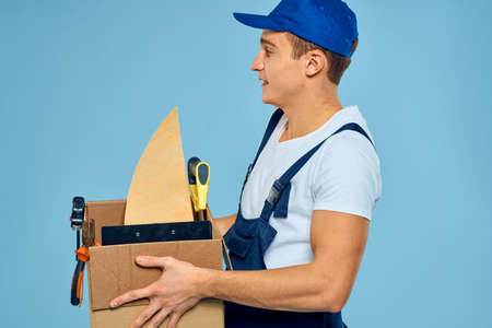 working man in uniform box with tools loader delivery blue background