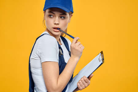 woman in work uniform documents courier service yellow background