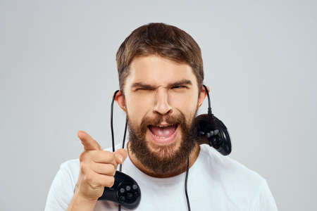 A man holds in his hands two joysticks playing leisure technology lifestyle white t-shirt