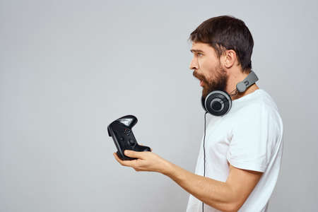 Man with gamepad headphones playing leisure technology white t-shirt light background