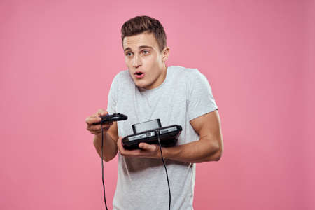 Cute man console in hands of video game entertainment lifestyle gray t-shirt pink background
