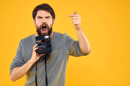Male photographer with professional photo camera. Professional Creative approach studio yellow...