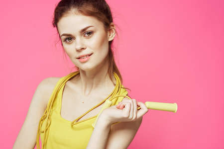 sportive woman jumping rope in hands yellow tank top pink background workout lifestyle