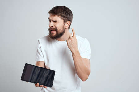 emotional man with tablet in hand touch screen new technologies light background cropped view Copy...