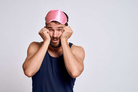 A man with a pink sleep mask AND a black T-shirt on a gray background cropped viewの写真素材