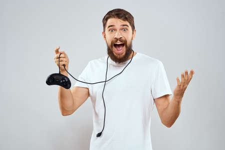 A man with a gamepad in his hands playing games leisure lifestyle technology white t-shirt light...
