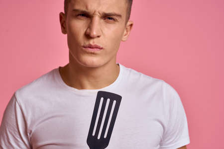 Man with kitchen tools on pink background spatula for cooking model cropped viewの写真素材