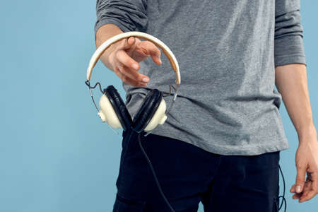 Headphones in man hands cropped view music technology blue background