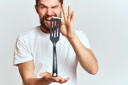 man with shovel for cooking white t-shirt cropped view light background