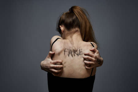 woman with offensive inscriptions on her body touching herself with hands stress frustration hateの写真素材