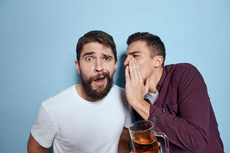 Two cheerful drunk friends drinking beer lifestyle emotions on a blue backgroundの写真素材