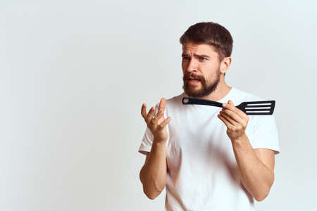 man with cooking shovel and white t-shirt close-up cropped view emotion gesturing with handの写真素材